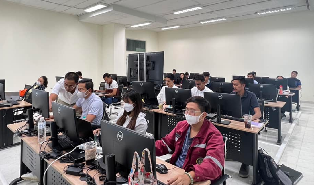 A group of people in a room with computers

Description automatically generated