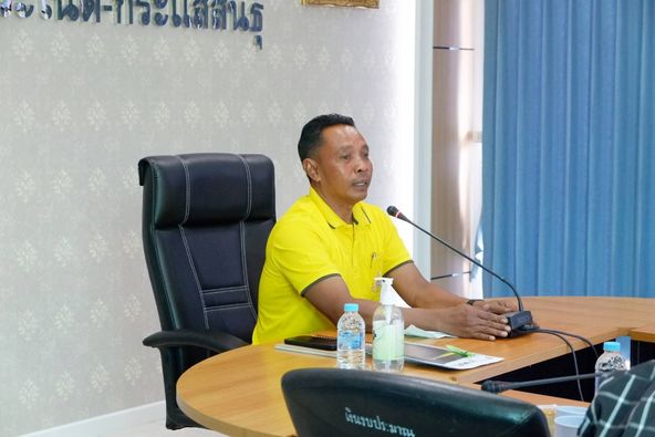 A person in a yellow shirt sitting at a table with a microphone

Description automatically generated