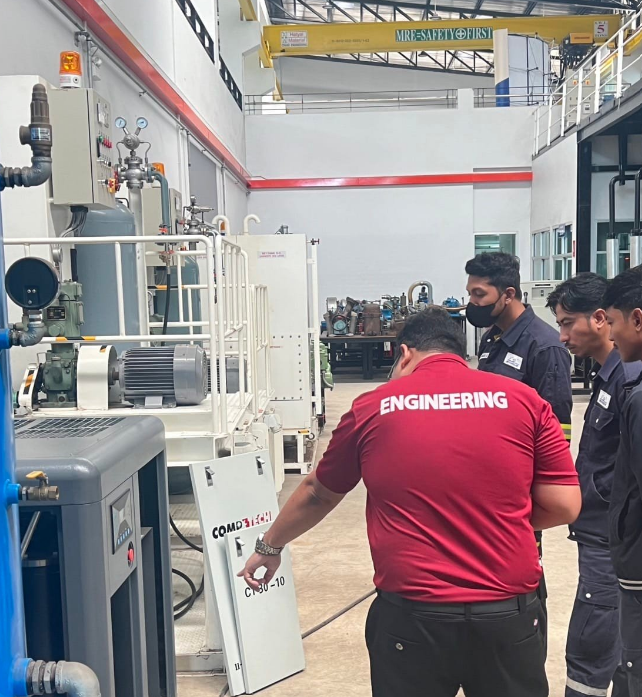 A group of men in a room with machines
Description automatically generated