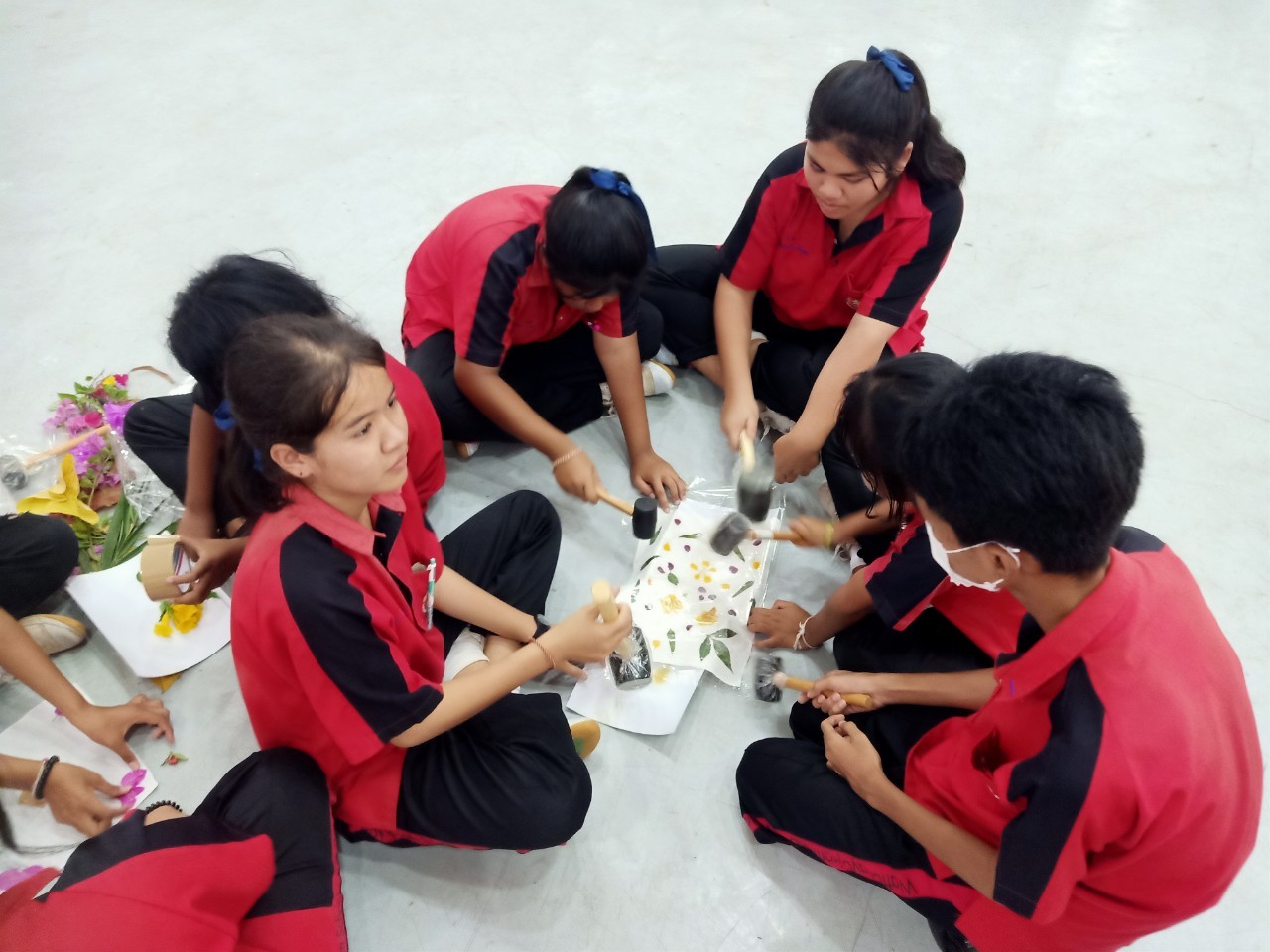 A group of people in red and black uniforms sitting on the floor

AI-generated content may be incorrect.