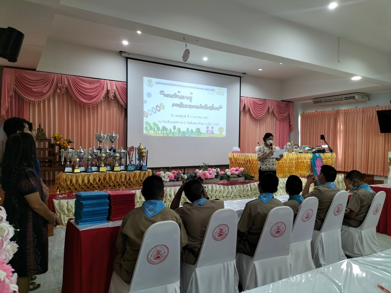 A group of people sitting in chairs in a room with a projector screen

AI-generated content may be incorrect.